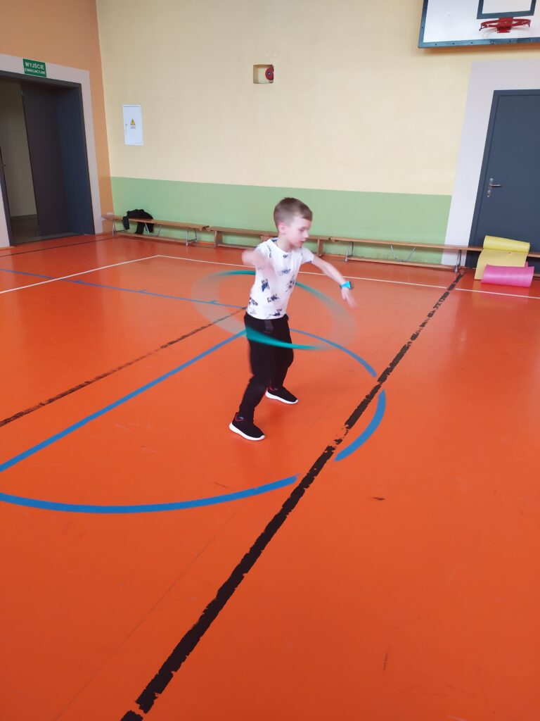 Uczeń kręci hula-hoop na biodrach.
