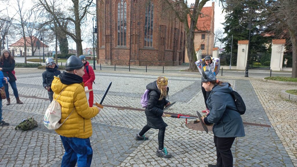  Uczniowie na placu udają bitwę.