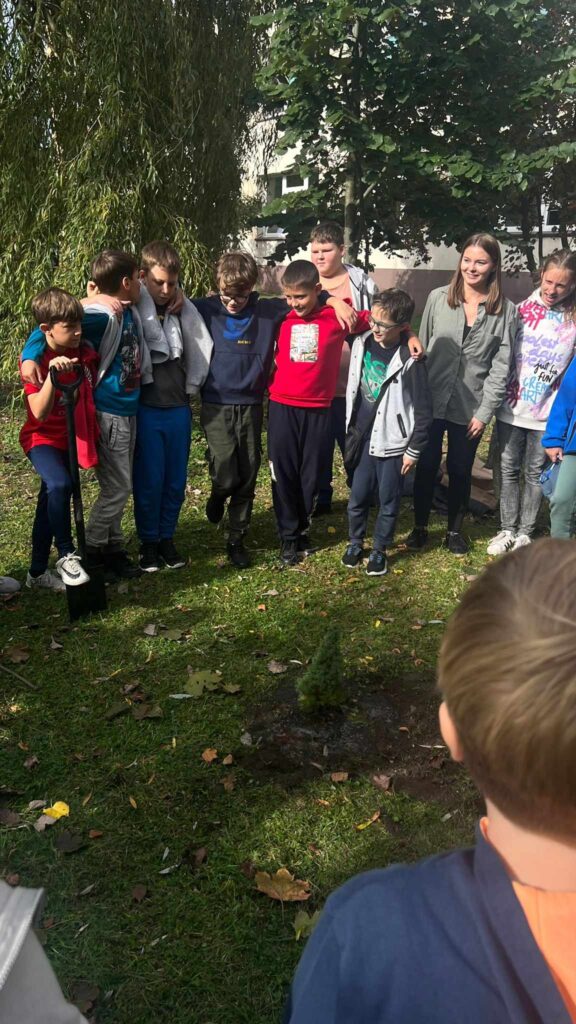 Na zdjęciu grupa ludzi. Jeden z chłopców trzyma łopatę.