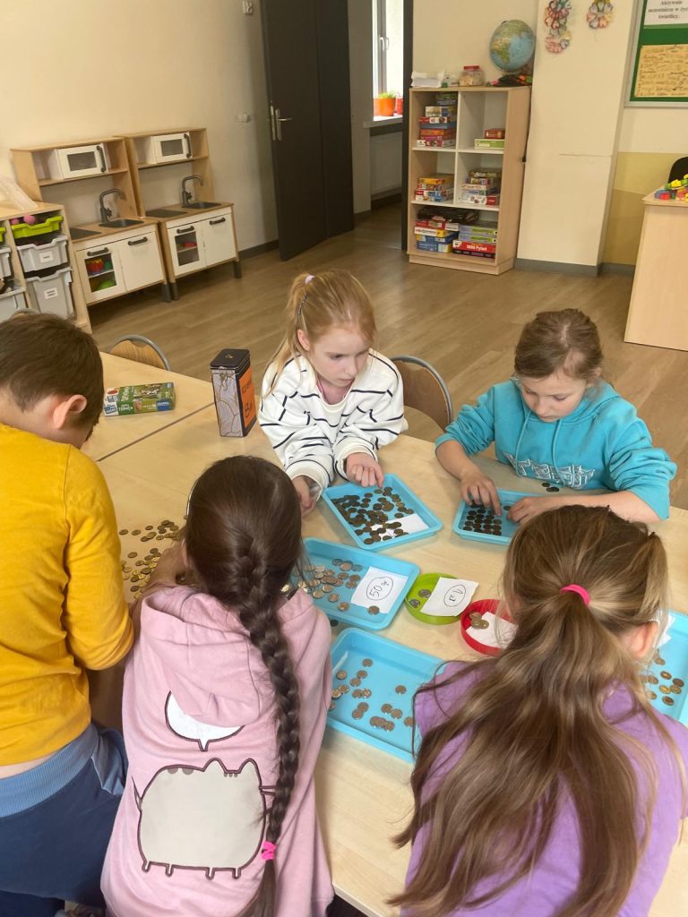 Uczniowie liczący i segregujący pieniądze.