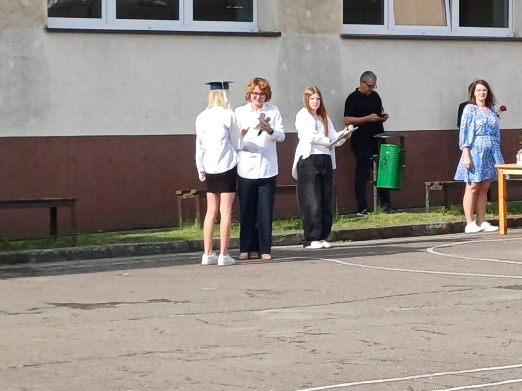 Uczennica odbiera dyplom i gratulacje z rąk Pani Dyrektor.