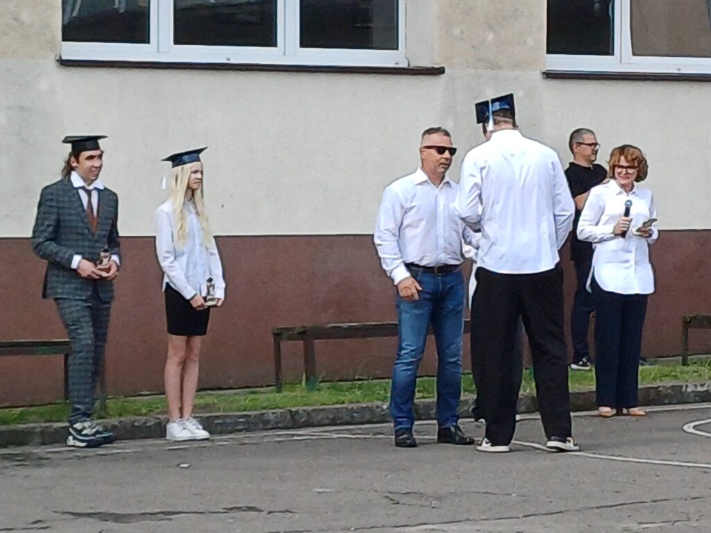Uczeń odbiera dyplom i gratulacje z rąk nauczyciela.