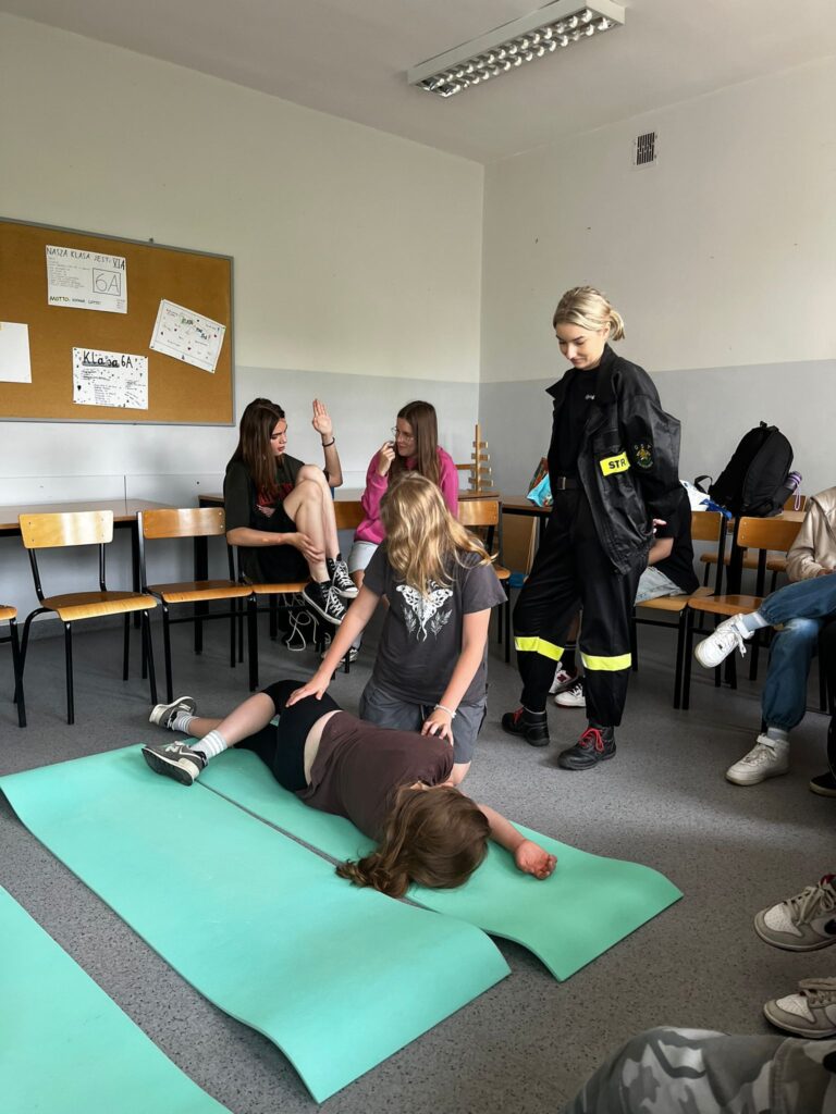 Dzieci wykonują pozycję boczną bezpieczną 