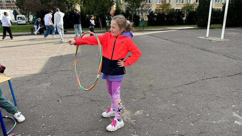 Uczennica kręcąca hula hop na przedramieniu.
