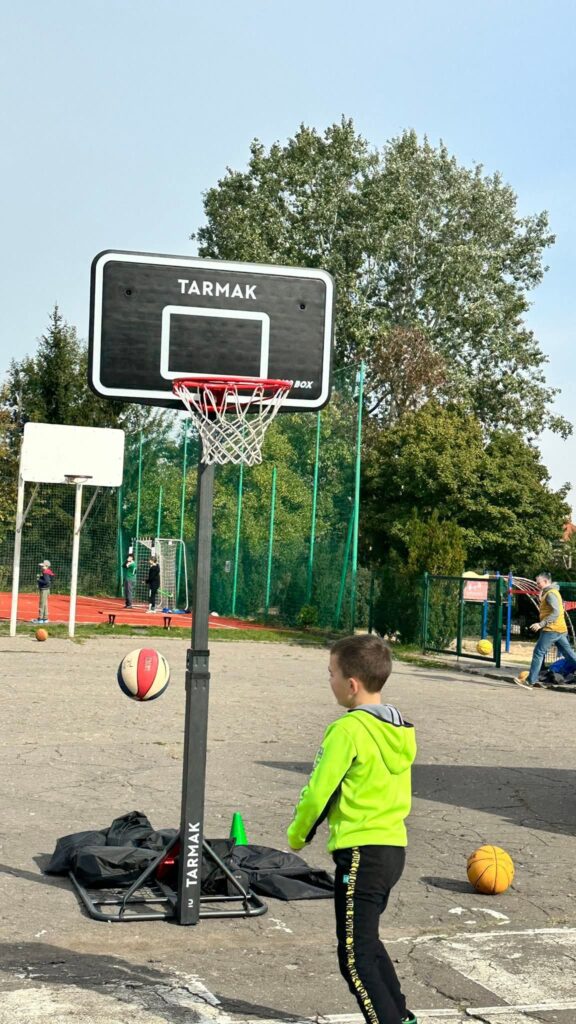 Uczeń rzucający piłką koszykową do kosza.