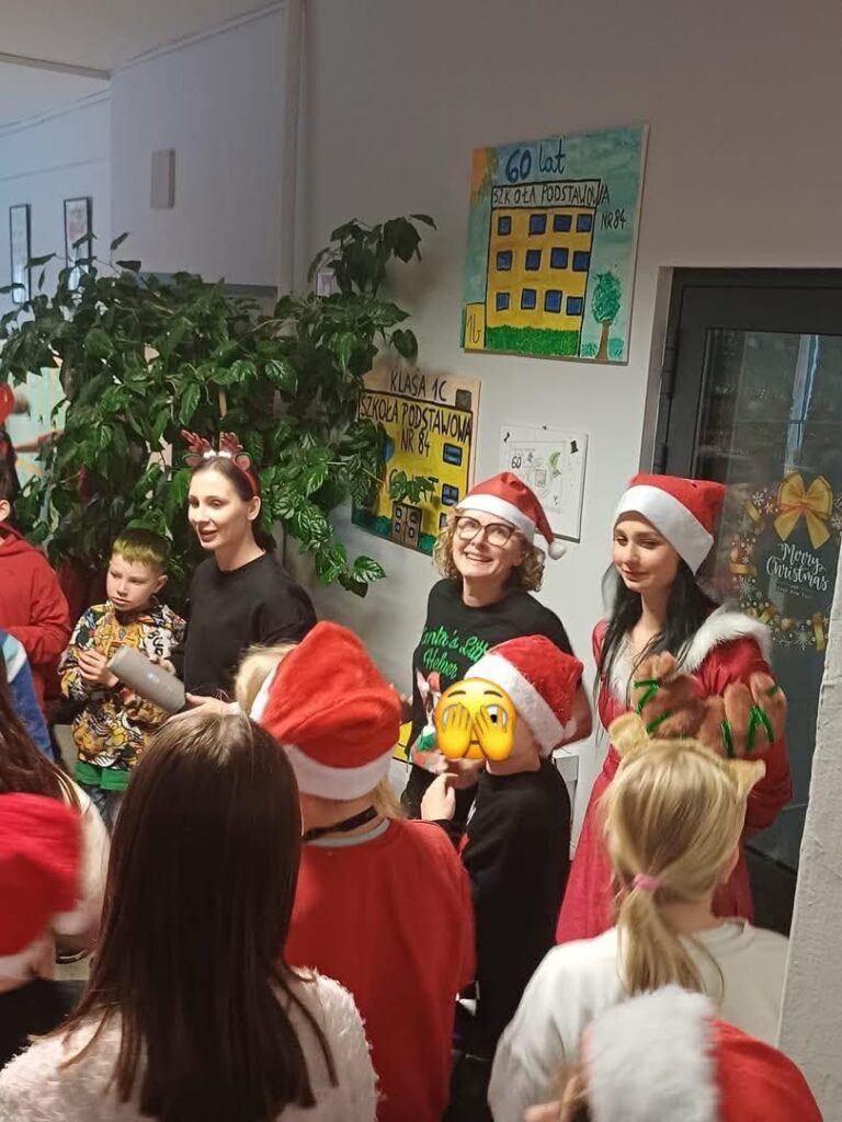 Pani Dyrektor w czapce Mikołaja wraz z uczniami , nauczycielką oraz rodzicem.