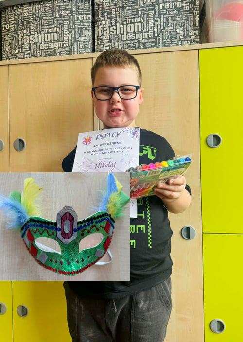 Uczeń trzymający dyplom, nagrodę stojący na tle szafek w sali.