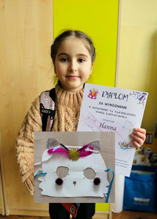 Uczennica trzymająca dyplom z nagrodą stojąca na tle drzwi od szafy.