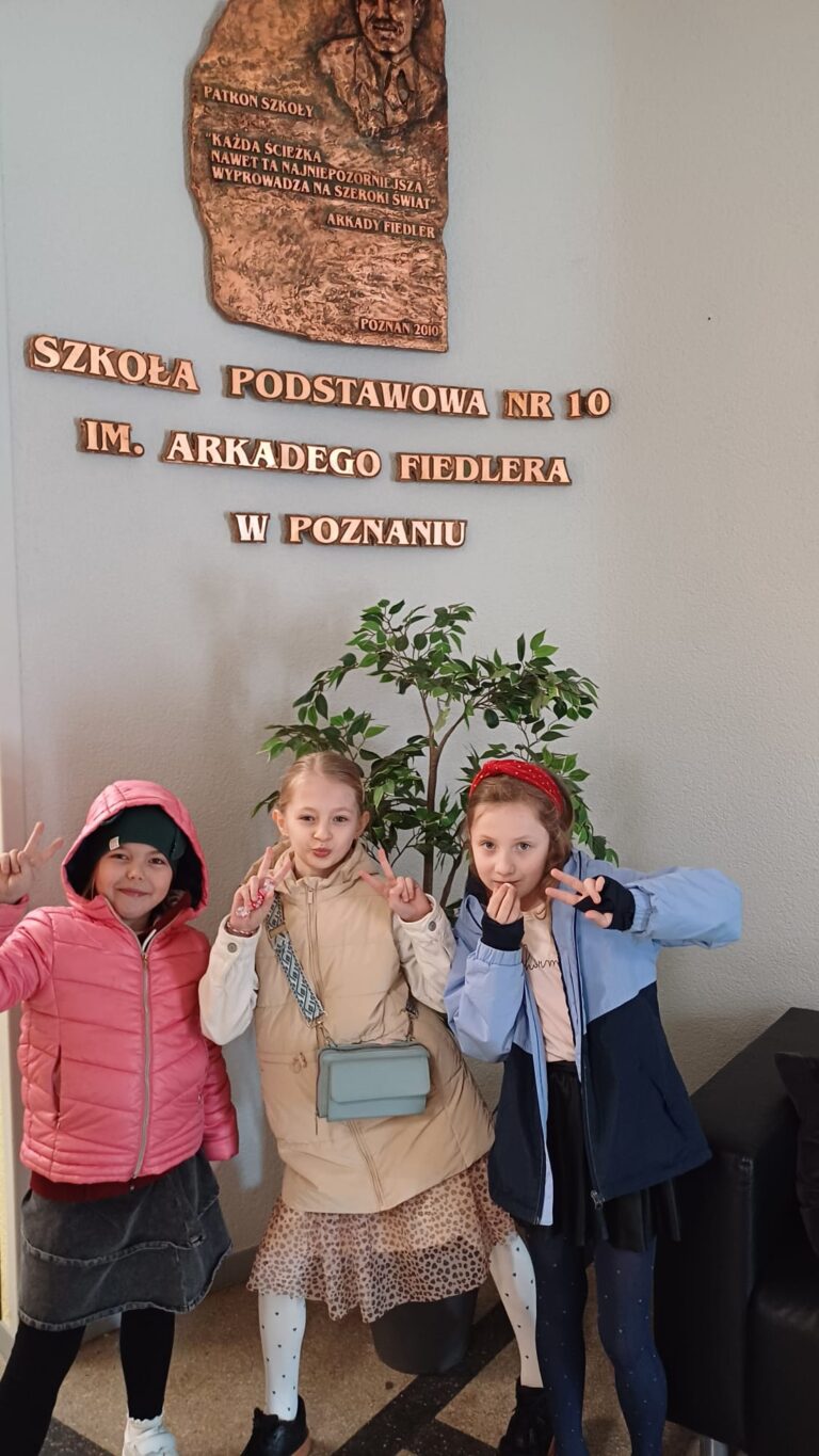 Uczennice stojące na tle ściany w szkole organizującej konkurs