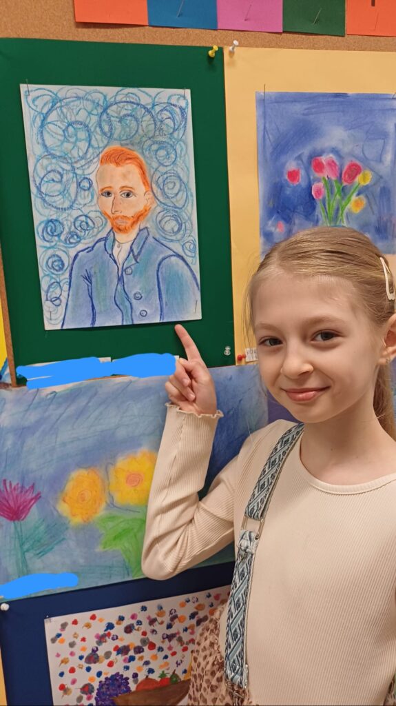 Uczennica wskazujące swoją pracę powieszoną na ściance.