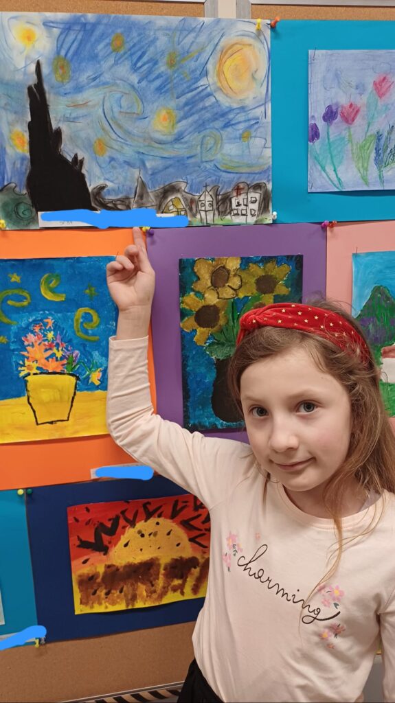 Uczennica wskazująca swoją pracę na tablicy.