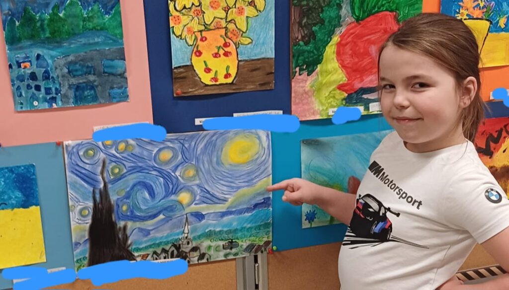 Uczennica wskazująca swoją pracę na ściance.