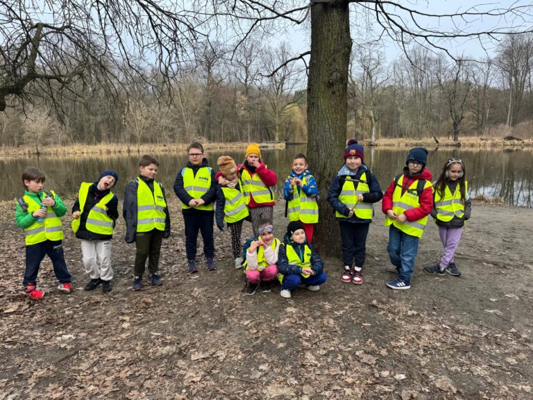 Klasa 1a stojąca w lesie na tle rzeki.