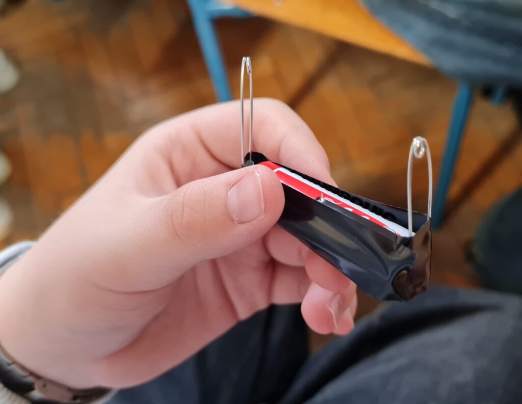 Uczeń trzyma baterie i tworzy elektromagnes