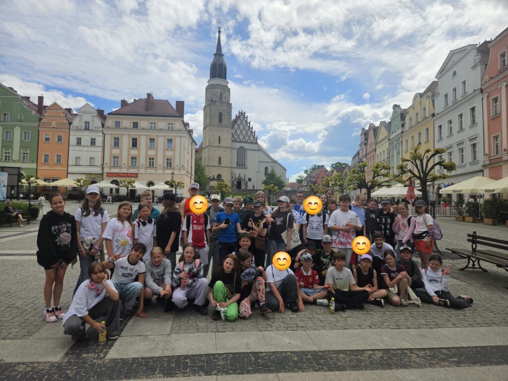 Uczniowie klas 4 na tle budynków na rynku.