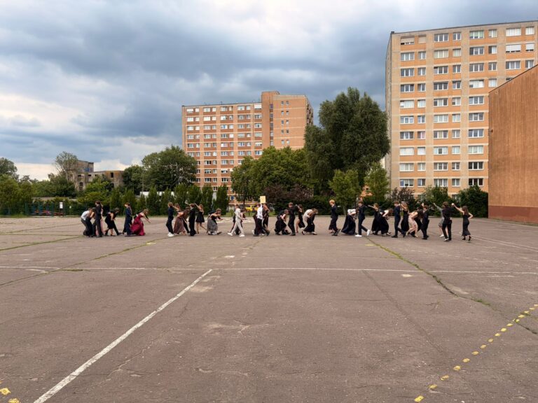 Uczniowie klas 8 tańczą poloneza na szkolnym boisku