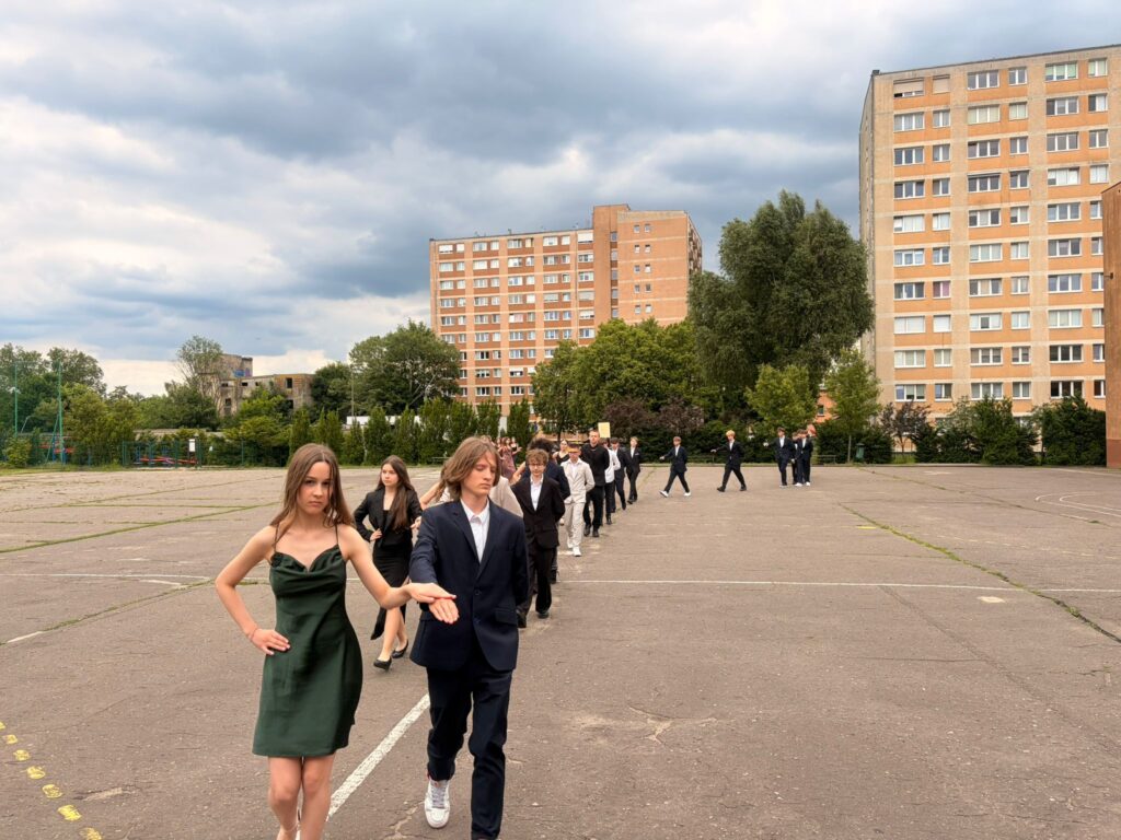 Uczniowie klas 8 tańczą poloneza na szkolnym boisku