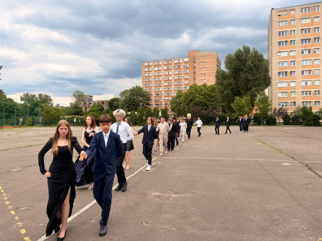 Uczniowie klas 8 tańczą poloneza na szkolnym boisku